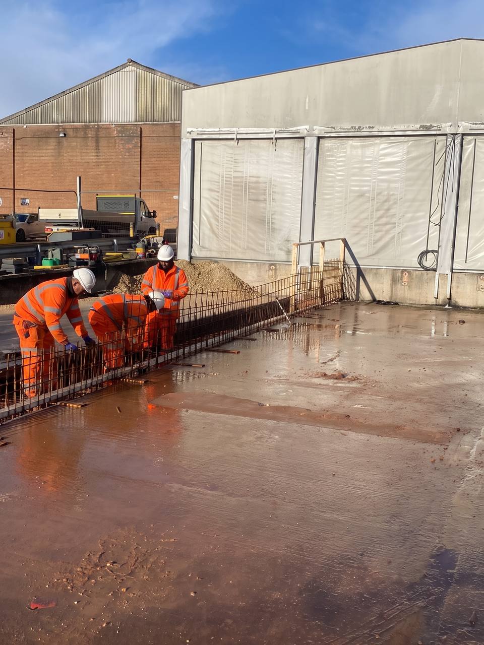 Crew fixing reinforcement on a slab in front of a hangar