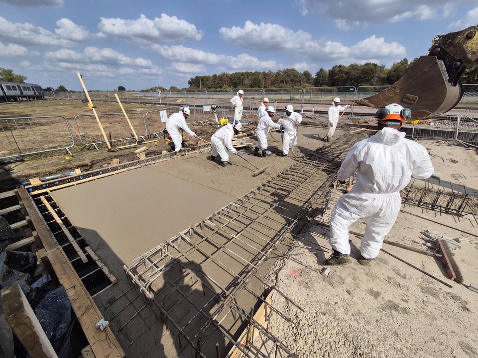 Crew raking and tamping a freshly poured slab